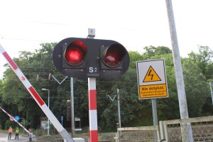 na zdjęciu widoczny jest sygnalizator S-2 nadający czerwone światło oraz zamykająca się zapora kolejowa
