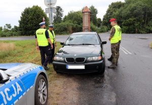policjanci Ruchu Drogowego wspólnie z funkcjonariuszami ZW dokonują kontroli drogowej pojazdu marki BMW