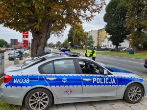 oznakowany radiowóz BMW, za nim stojących dwóch policjantów